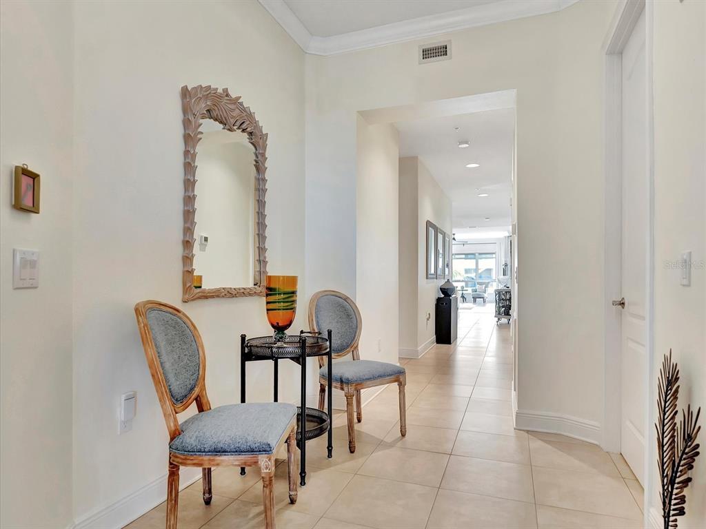 A foyer features two upholstered chairs, a small round table, and a mirror on the wall — 1022 BELLASOL WAY UNIT 5302, APOLLO BEACH, FL