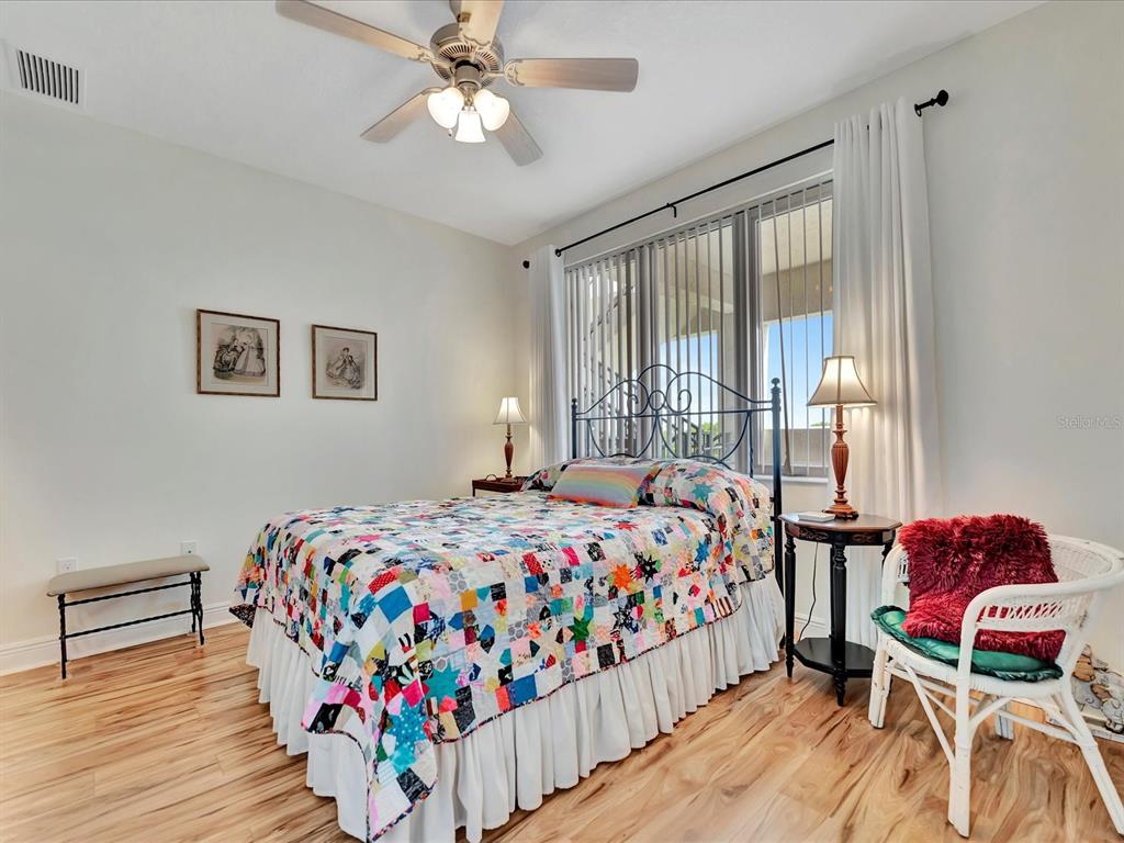 A bedroom features a patchwork quilt on the bed, a ceiling fan, and wood flooring — 1022 BELLASOL WAY UNIT 5302, APOLLO BEACH, FL