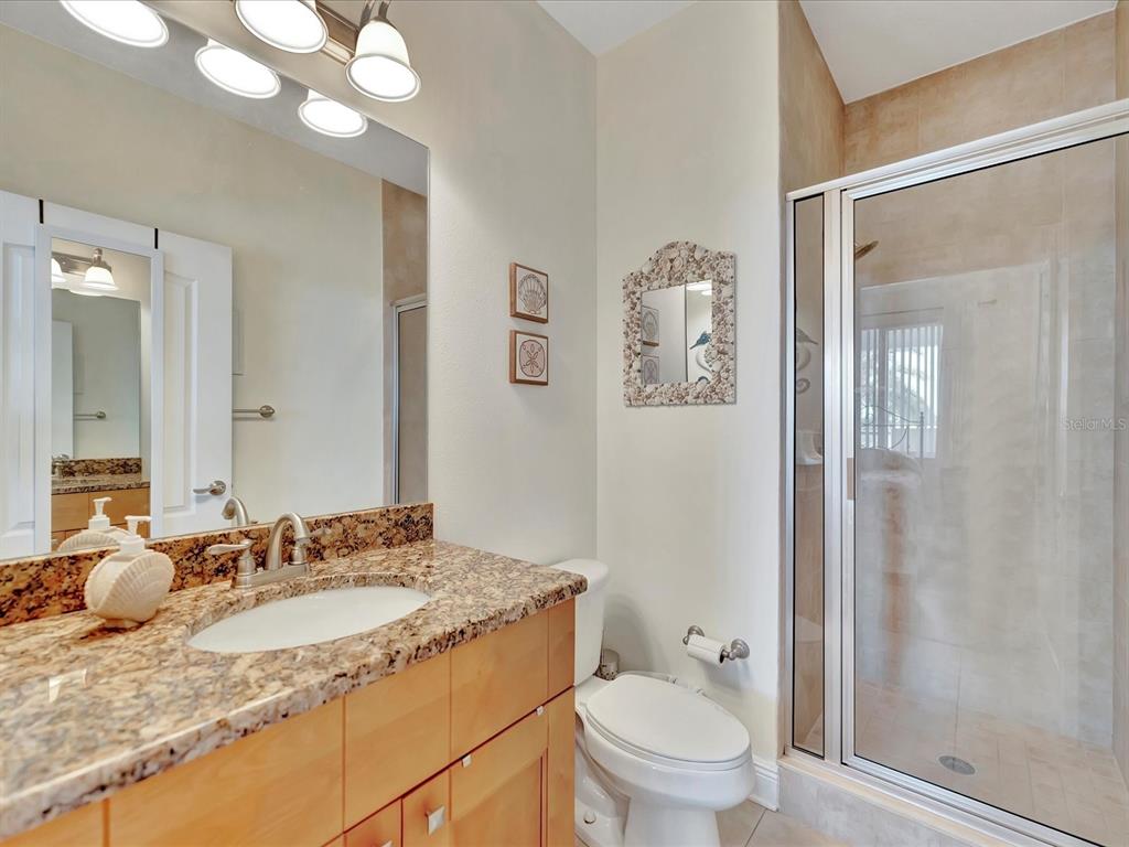 A bathroom features a granite vanity, a toilet, and a glass-enclosed walk-in shower — 1022 BELLASOL WAY UNIT 5302, APOLLO BEACH, FL