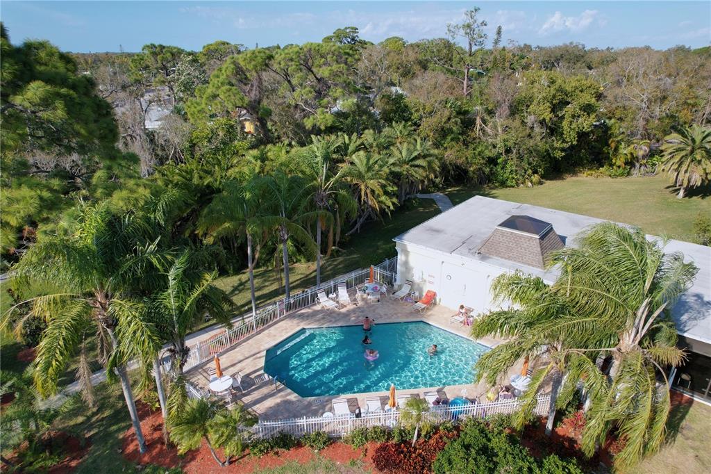 An aerial view of a swimming pool with lounge chairs and a clubhouse building — 11273 KAPOK GRAND CIRCLE, MADEIRA BEACH, FL