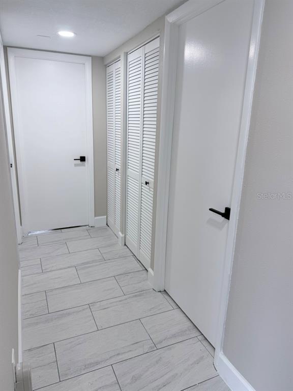 A hallway features light wood-look tile flooring, white doors with black hardware, and louvered closet doors — 3300 COVE CAY DRIVE UNIT 2A, CLEARWATER, FL