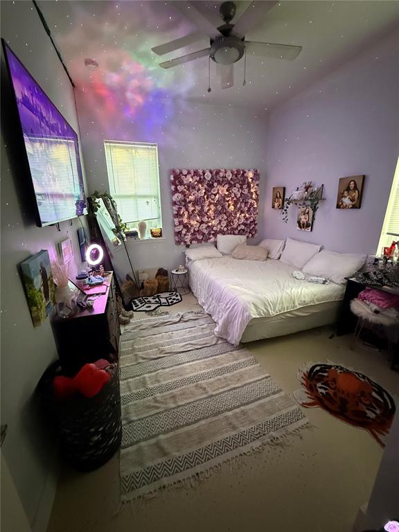 A bedroom features a bed with white bedding, a floral wall accent, and a ceiling projector — 727 NW 4TH AVENUE, GAINESVILLE, FL