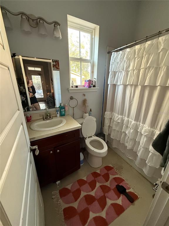 A bathroom features a dark wood vanity, a white toilet, and a ruffled shower curtain — 727 NW 4TH AVENUE, GAINESVILLE, FL