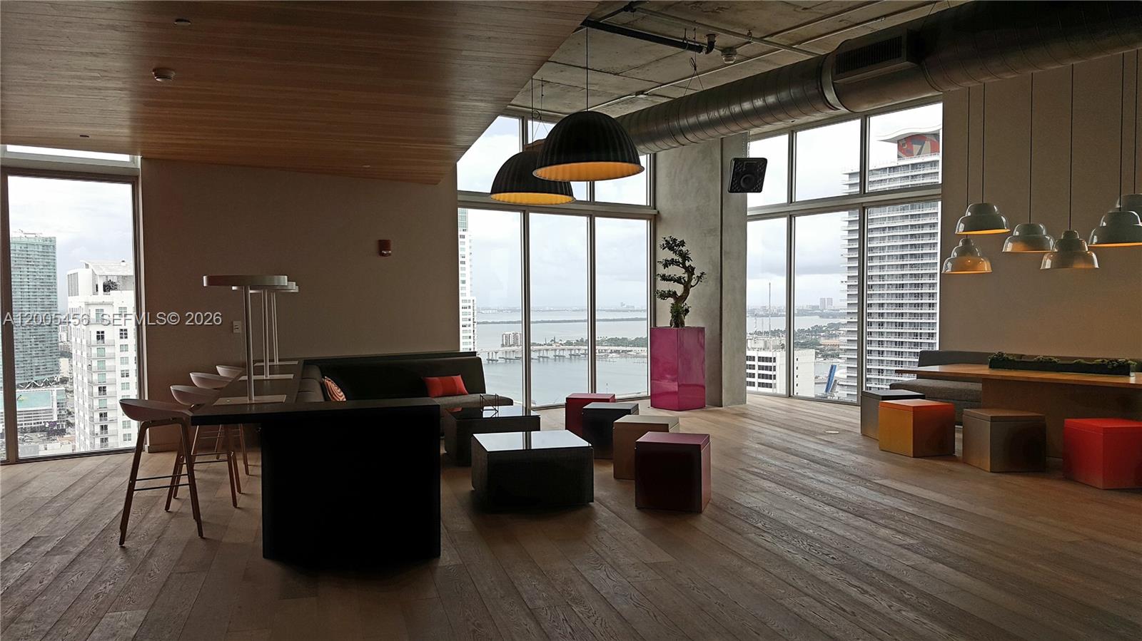 A modern lounge area features floor-to-ceiling windows, hardwood floors, and a view of the city — 151 SE 1st St # 1609, Miami FL 33131, MIAMI, FL