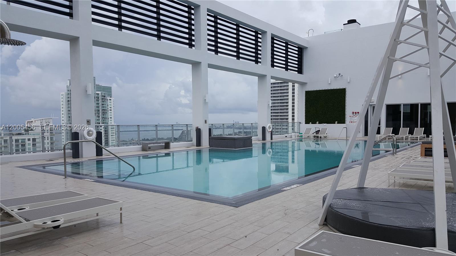 A rooftop swimming pool features a modern deck, lounge chairs, and views of city buildings — 151 SE 1st St # 1609, Miami FL 33131, MIAMI, FL