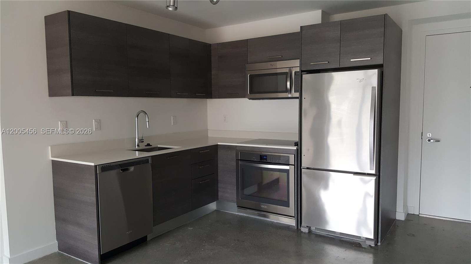 A modern kitchen features dark wood cabinets, stainless steel appliances, and light-colored countertops — 151 SE 1st St # 1609, Miami FL 33131, MIAMI, FL