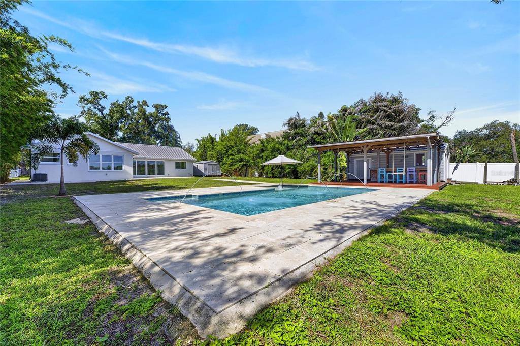 A backyard features a rectangular swimming pool with fountains, a patio, and a covered outdoor structure — 6712 MYRNA DRIVE, TAMPA, FL