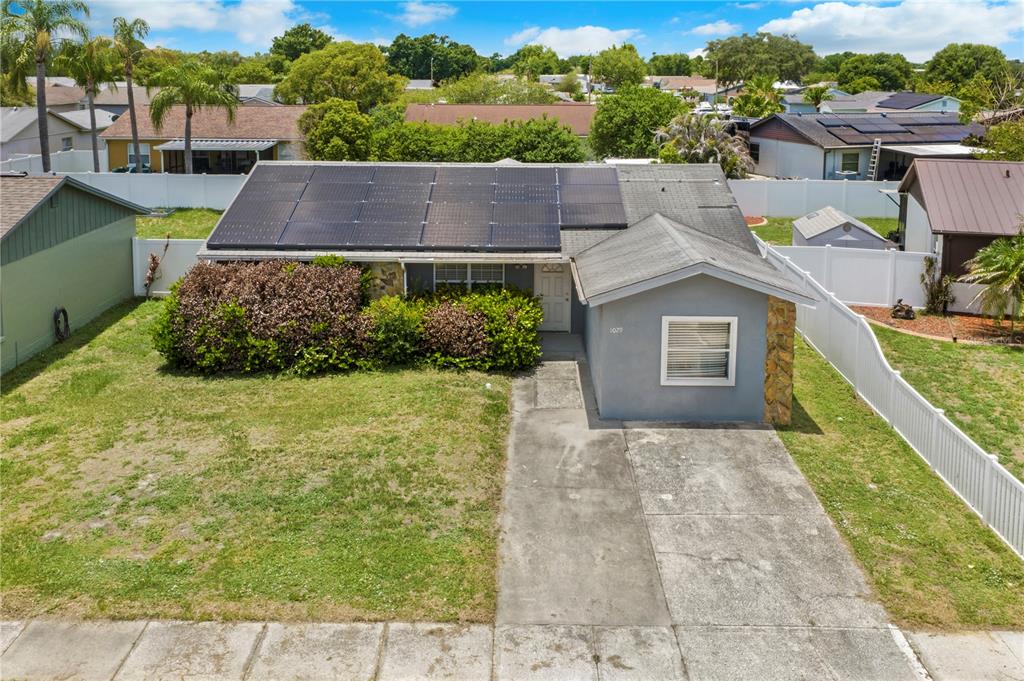 An aerial view shows a single-story house with solar panels on the roof and driveway — 1029 PINE RIDGE CIRCLE, BRANDON, FL