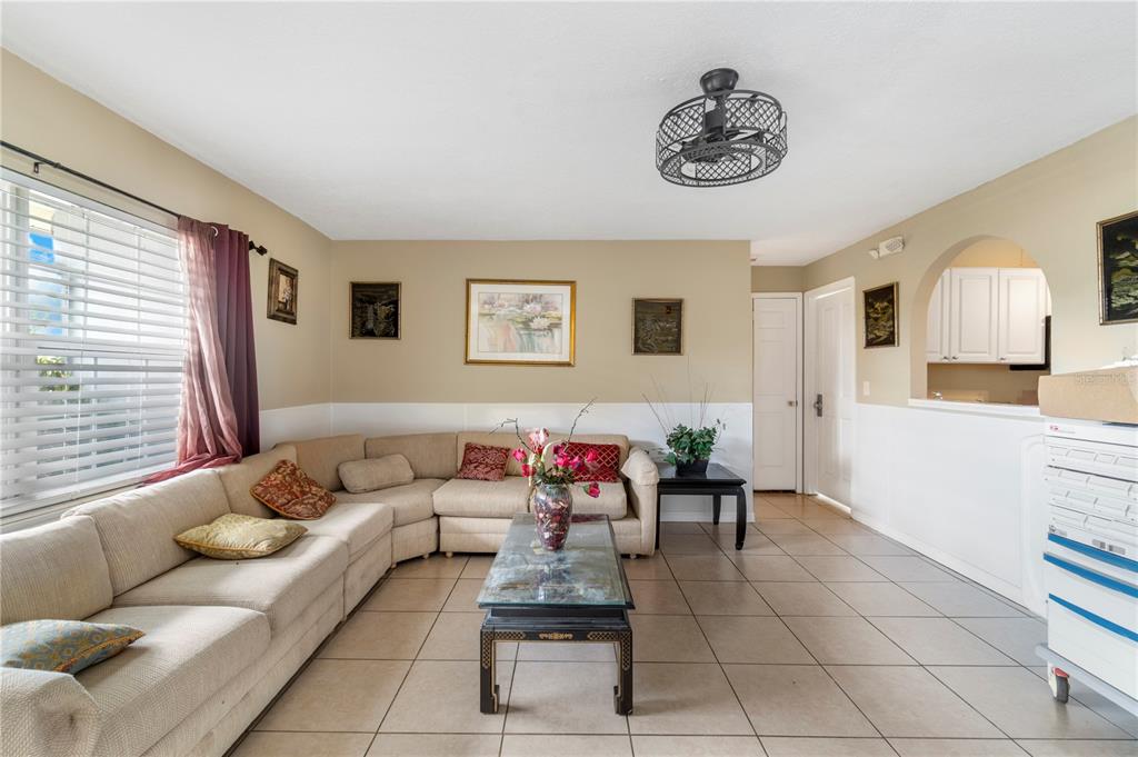 A living room features a beige sectional sofa, tile flooring, and a ceiling fan — 1029 PINE RIDGE CIRCLE, BRANDON, FL