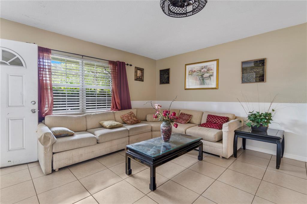 A living room features a beige sectional sofa, a glass-top coffee table, and tile flooring — 1029 PINE RIDGE CIRCLE, BRANDON, FL