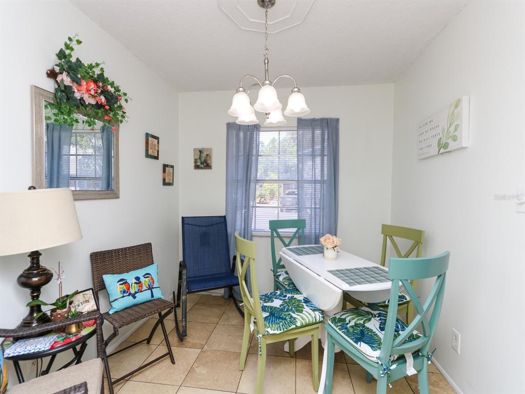 A dining area features a white table, assorted chairs, a chandelier, and tile flooring — 3021 AARON BURR AVENUE UNIT 3, WINTER PARK, FL