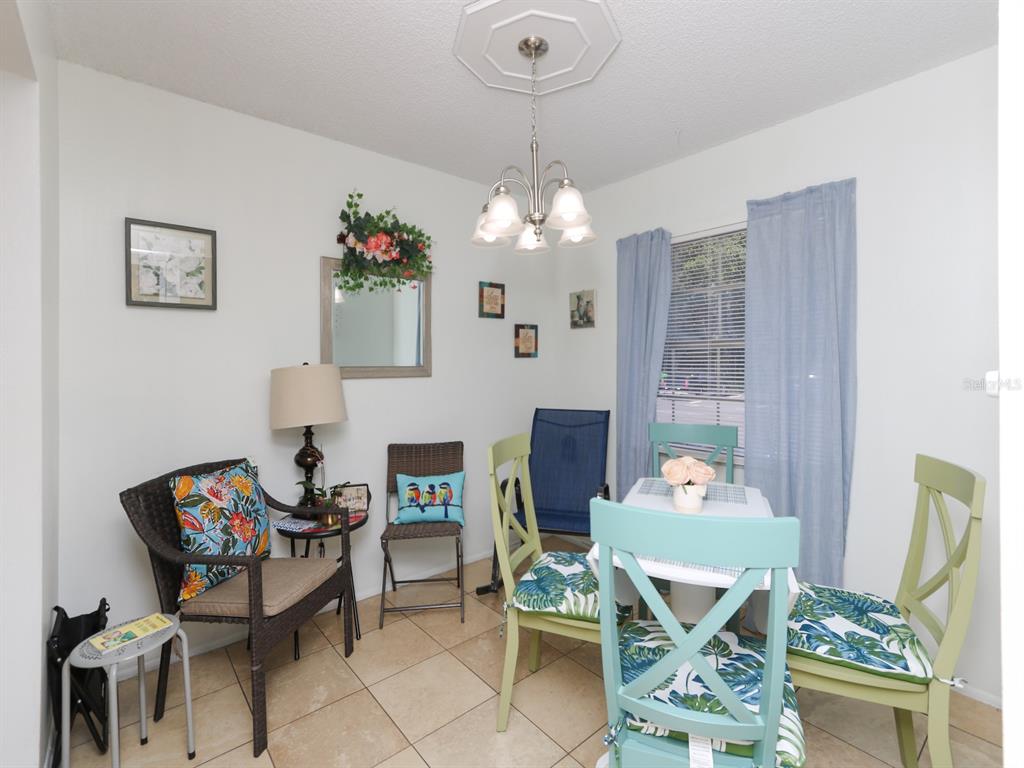 A dining area features a light-colored table with four chairs, tile flooring, and a chandelier — 3021 AARON BURR AVENUE UNIT 3, WINTER PARK, FL