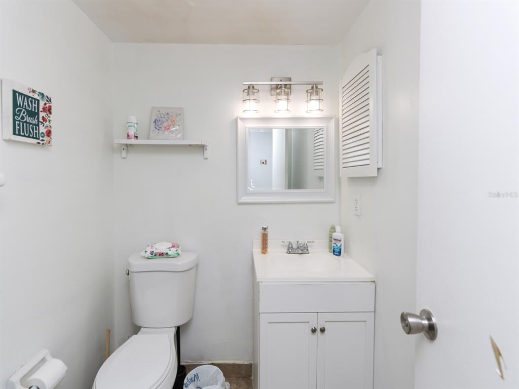 A small bathroom features a white vanity, a toilet, a mirror, and a wall shelf — 3021 AARON BURR AVENUE UNIT 3, WINTER PARK, FL
