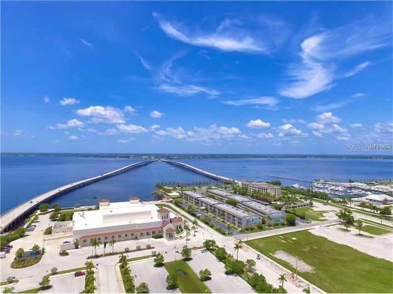 An aerial view shows a large building, parking lots, and a long bridge over water — 2267 CANNOLOT BOULEVARD, PORT CHARLOTTE, FL