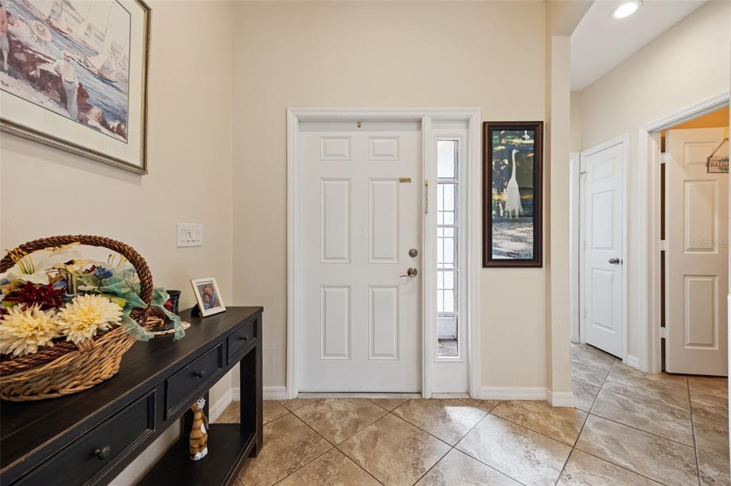 An entryway features a white front door, tiled floors, a console table, and wall art — 8648 LAKE FRONT COURT, PUNTA GORDA, FL