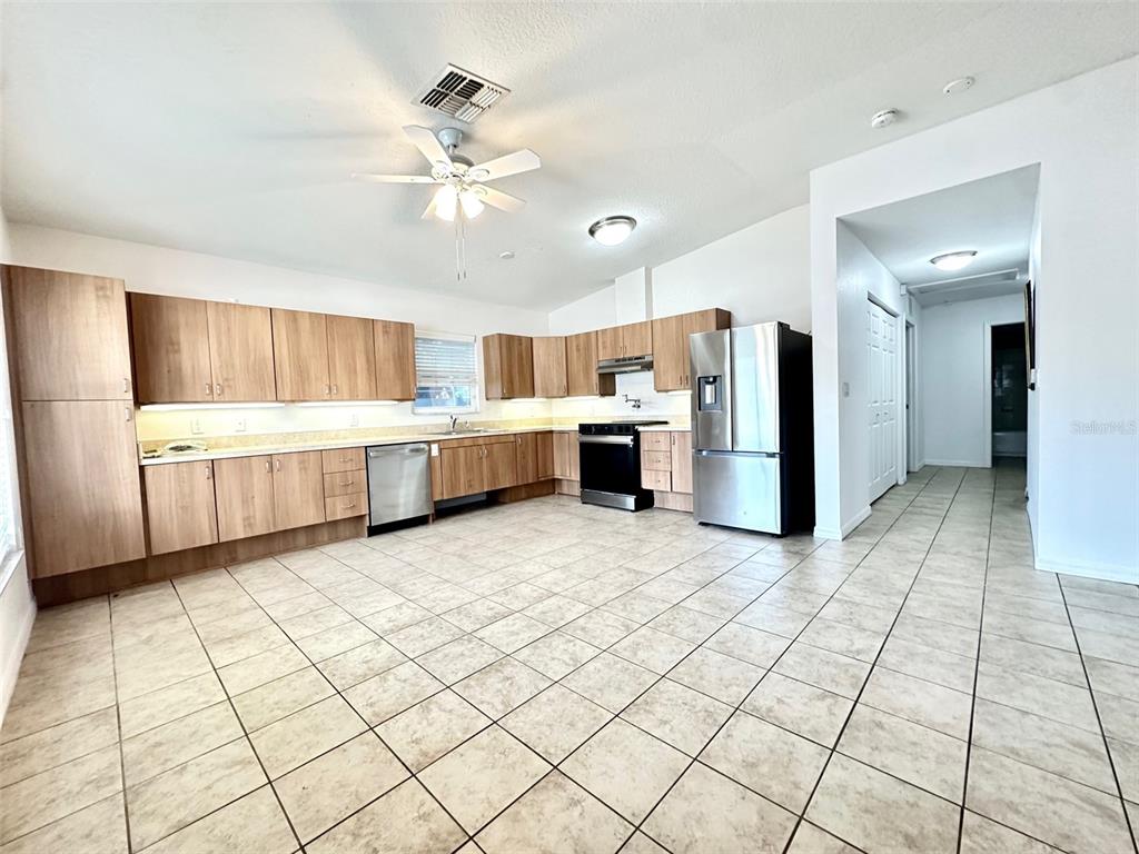 A kitchen features light wood cabinets, stainless steel appliances, and beige tile flooring — 1121 DR MARTIN LUTHER KING JR STREET S, ST PETERSBURG, FL