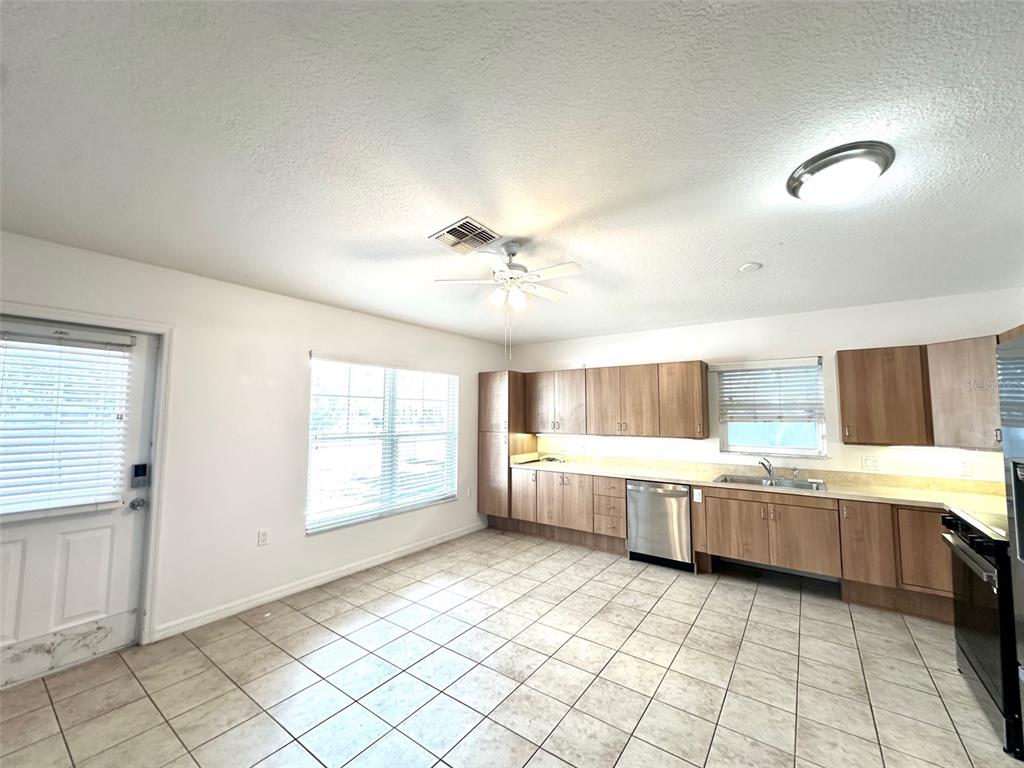 A kitchen with light-colored tile flooring, wood cabinets, stainless steel appliances, and a ceiling fan — 1121 DR MARTIN LUTHER KING JR STREET S, ST PETERSBURG, FL