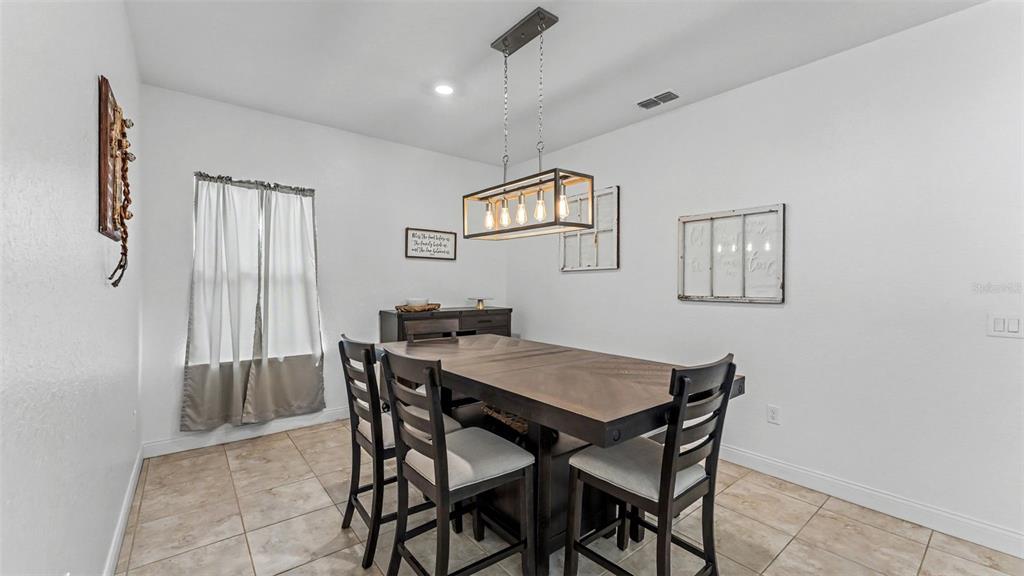 A dining room features a wooden table, four chairs, a pendant light, and tiled flooring — 4129 TIMBER VALLEY WAY, LAKELAND, FL