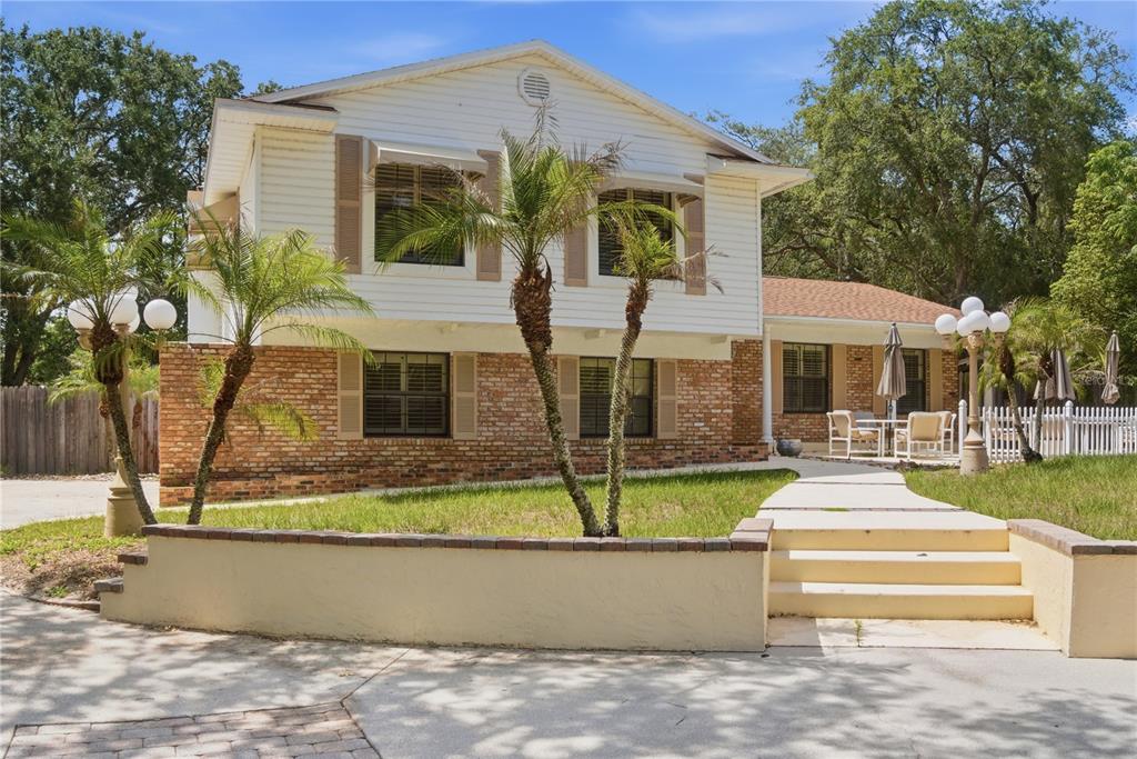 A two-story house with white siding, brick lower walls, palm trees, and a front walkway — 1204 SWAN STREET, WINTER SPRINGS, FL