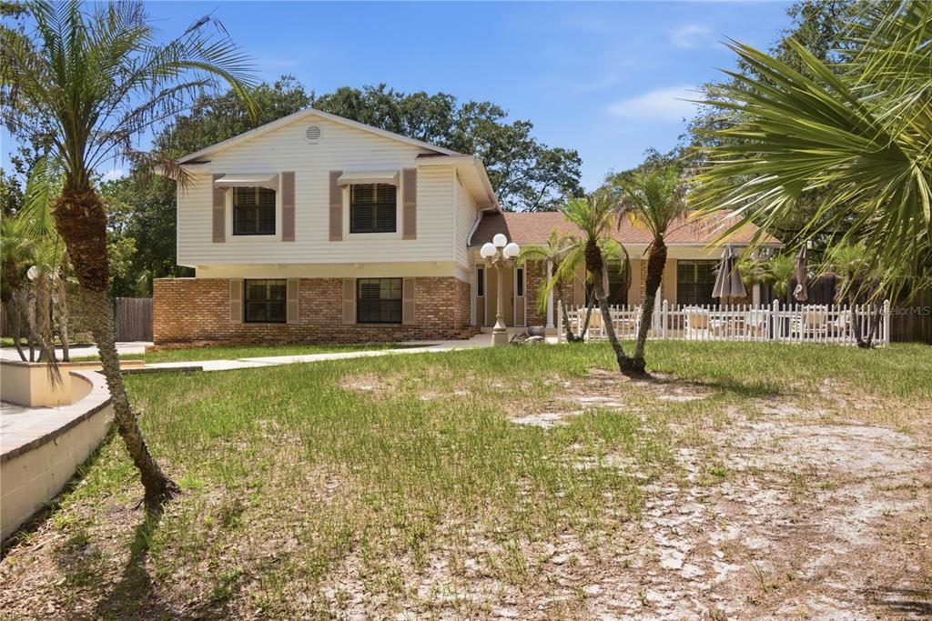 A two-story house with white siding and brick accents features a front yard and palm trees — 1204 SWAN STREET, WINTER SPRINGS, FL