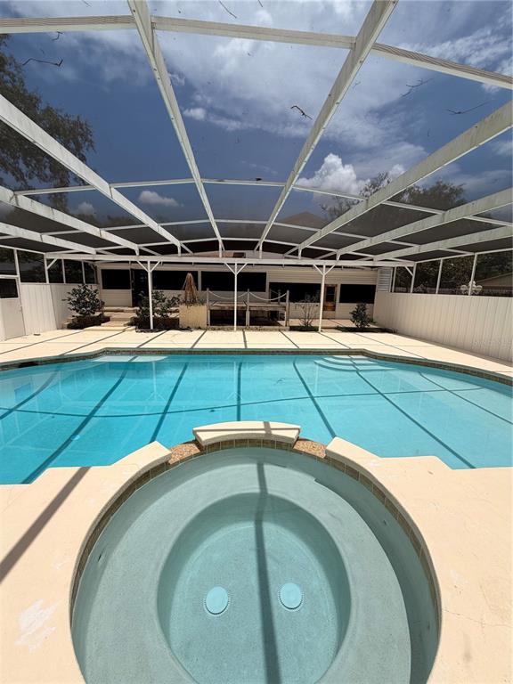 A screened-in swimming pool and hot tub area with a light-colored concrete deck — 1204 SWAN STREET, WINTER SPRINGS, FL