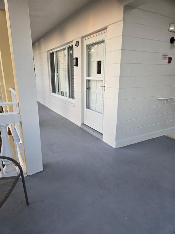 A white exterior wall with a storm door, a window, and a gray concrete walkway — 2430 FLORENTINE WAY UNIT 40, CLEARWATER, FL