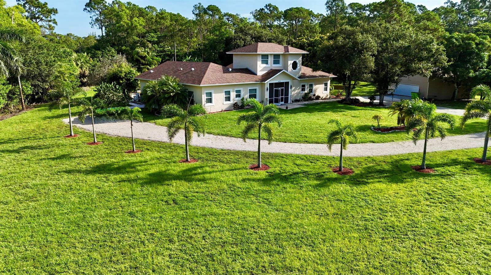 An aerial view of a tan house with a brown roof surrounded by palm trees — 14717 11th Terrace, FL 33470, FL