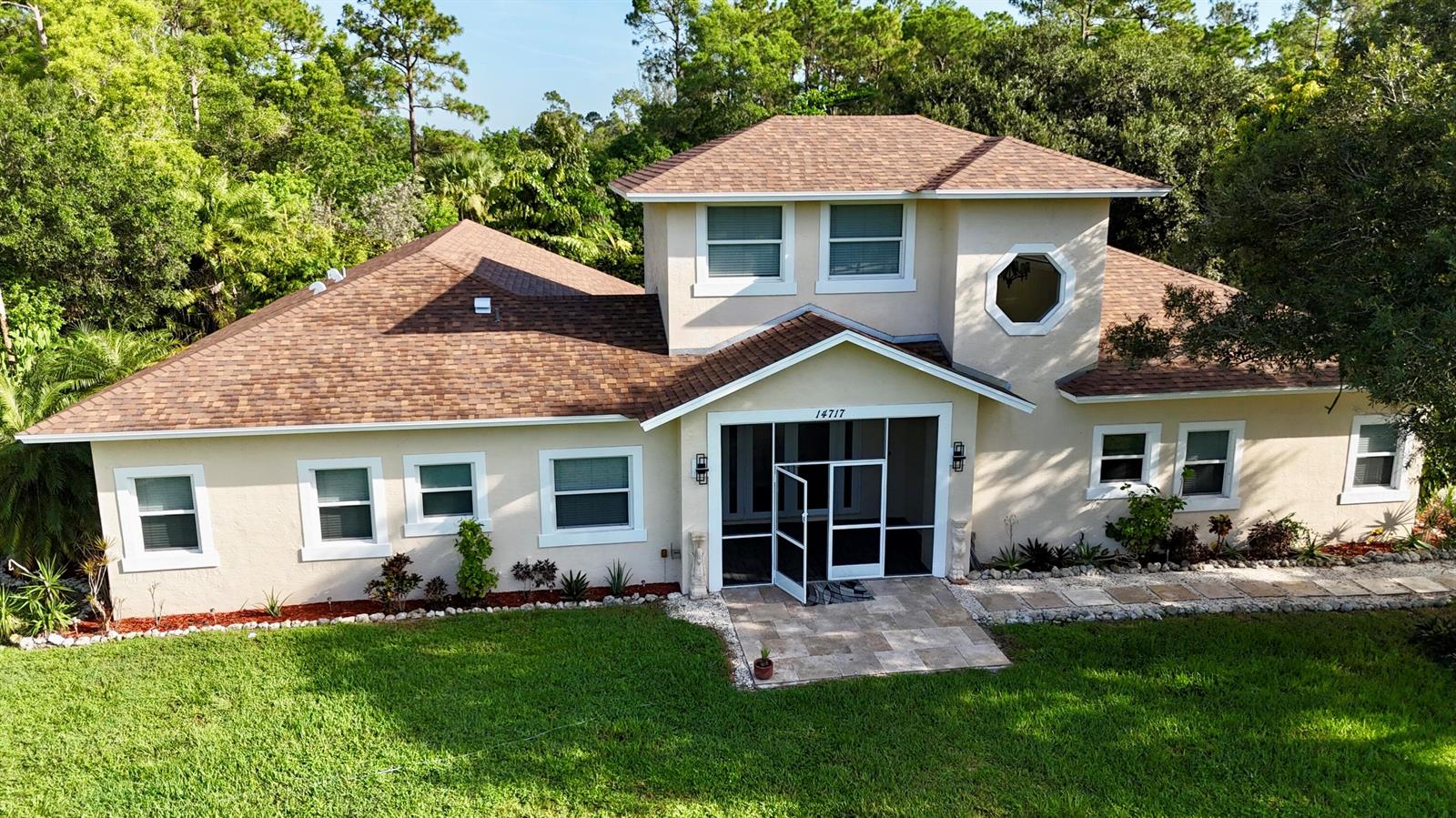 An aerial view of a two-story house with a brown shingled roof and beige stucco — 14717 11th Terrace, FL 33470, FL