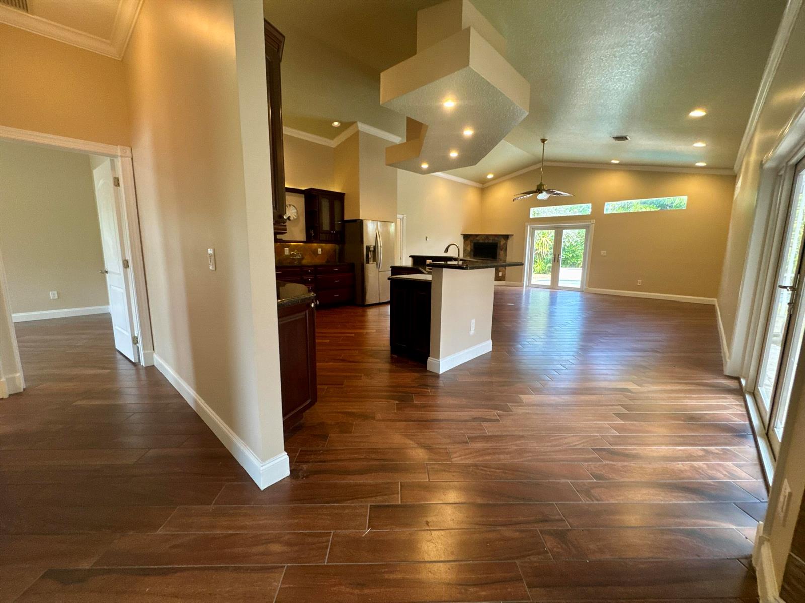 An open-concept kitchen and living area featuring dark wood cabinets, a kitchen island, and flooring — 14717 11th Terrace, FL 33470, FL