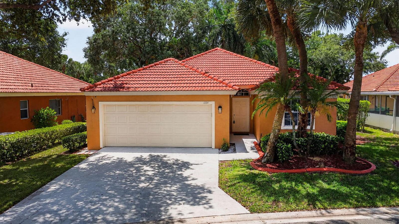 A single-story house with an orange stucco exterior, a red tile roof, and a garage — 1084 Aspri Way, Riviera Beach FL 33418, RIVIERA BEACH, FL