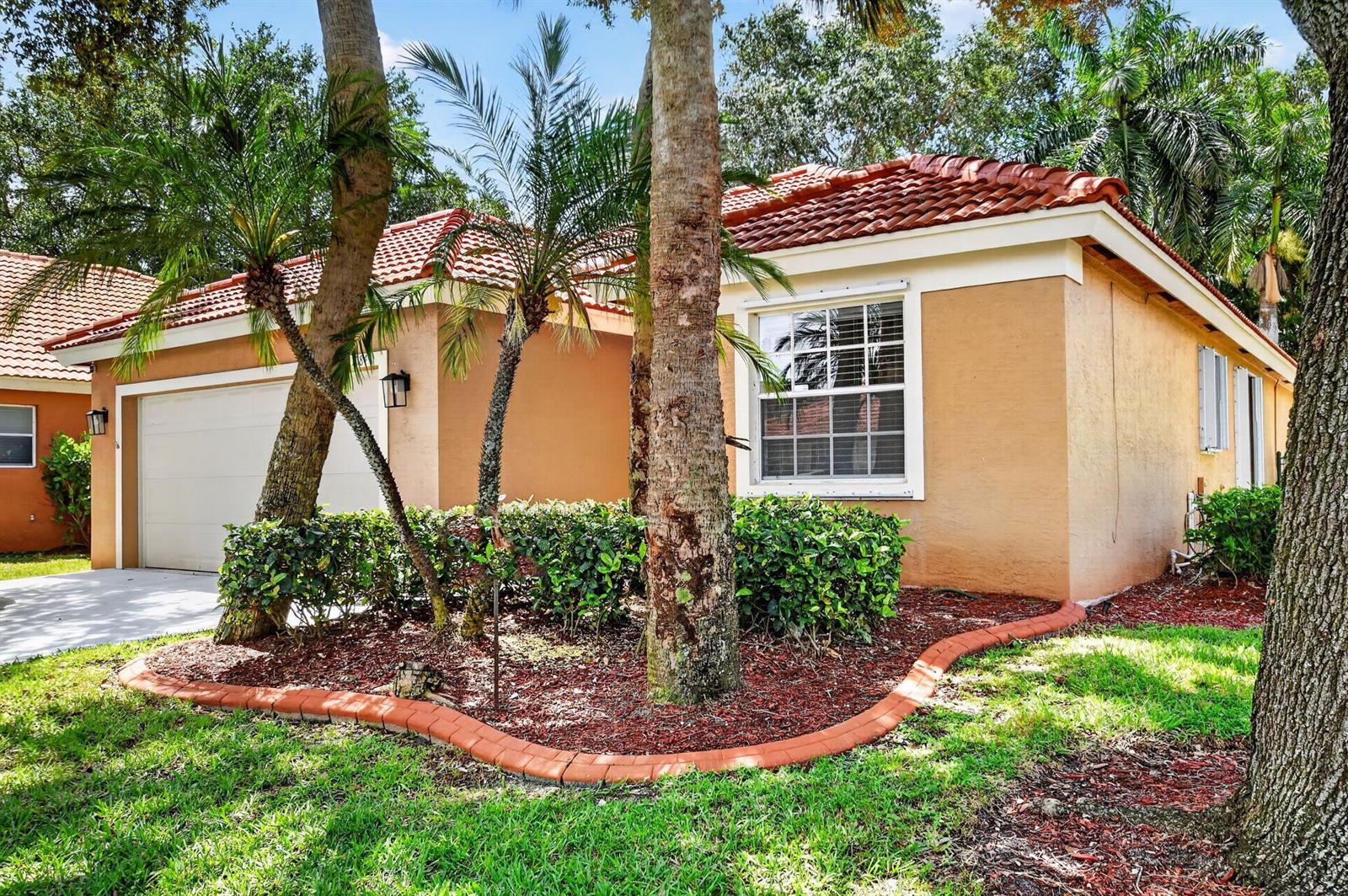 A single-story house with a tan stucco exterior, tile roof, and a front-facing garage — 1084 Aspri Way, Riviera Beach FL 33418, RIVIERA BEACH, FL