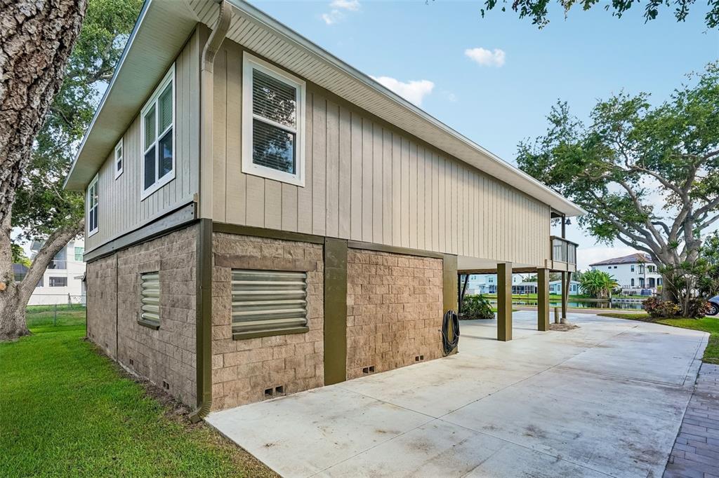 An elevated house with a concrete block foundation and a covered parking area underneath — 300 90TH AVENUE NE, ST PETERSBURG, FL