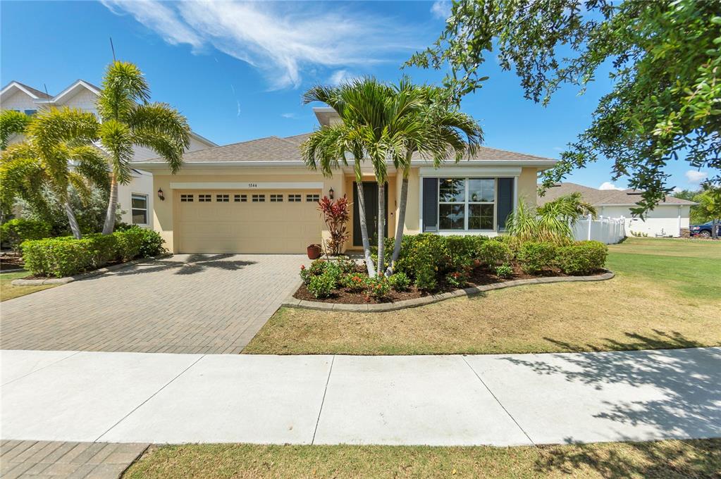 A single-story house with a beige exterior, a two-car garage, and a landscaped front yard — 5344 WISHING ARCH DRIVE, APOLLO BEACH, FL