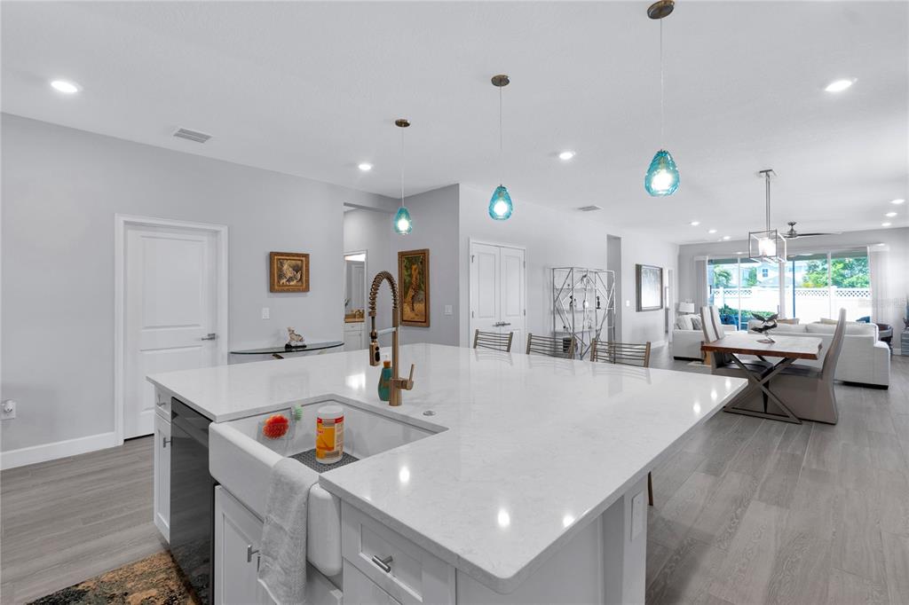 A bright kitchen features a large white quartz island with a farmhouse sink and pendant lights — 5344 WISHING ARCH DRIVE, APOLLO BEACH, FL