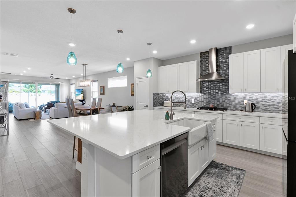 A modern kitchen with white cabinetry, a large quartz island, and a tiled backsplash — 5344 WISHING ARCH DRIVE, APOLLO BEACH, FL
