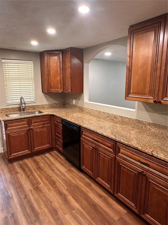 A kitchen features wood cabinets, granite countertops, a stainless steel sink, and wood-look flooring — 855 STEWART STREET, ENGLEWOOD, FL