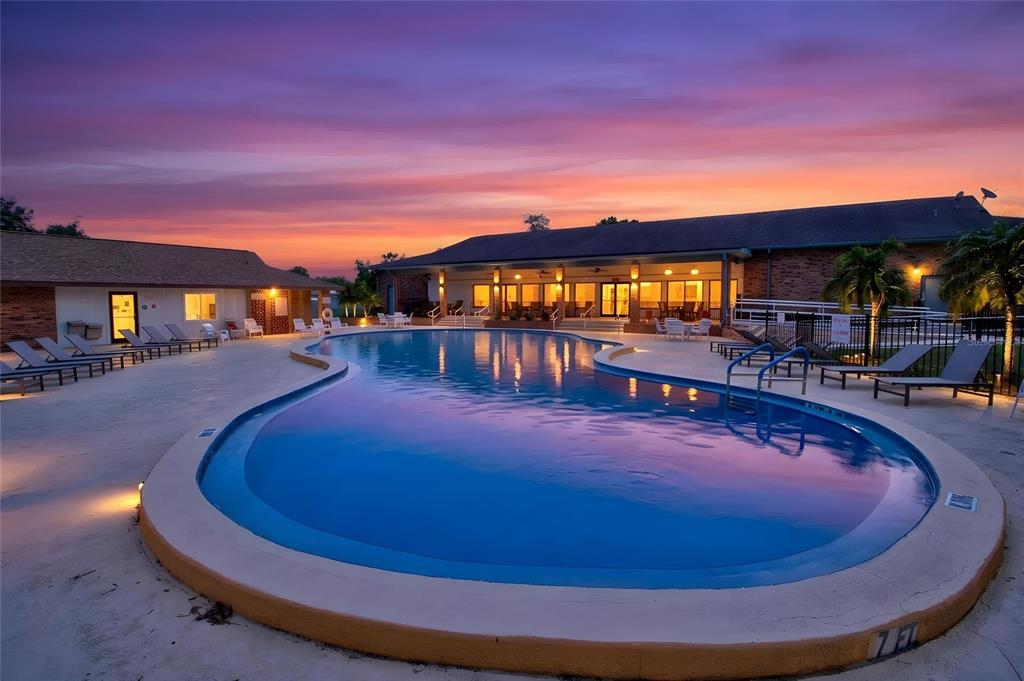 A kidney-shaped swimming pool sits in front of a building at sunset — 10081 SW 95TH AVENUE, OCALA, FL