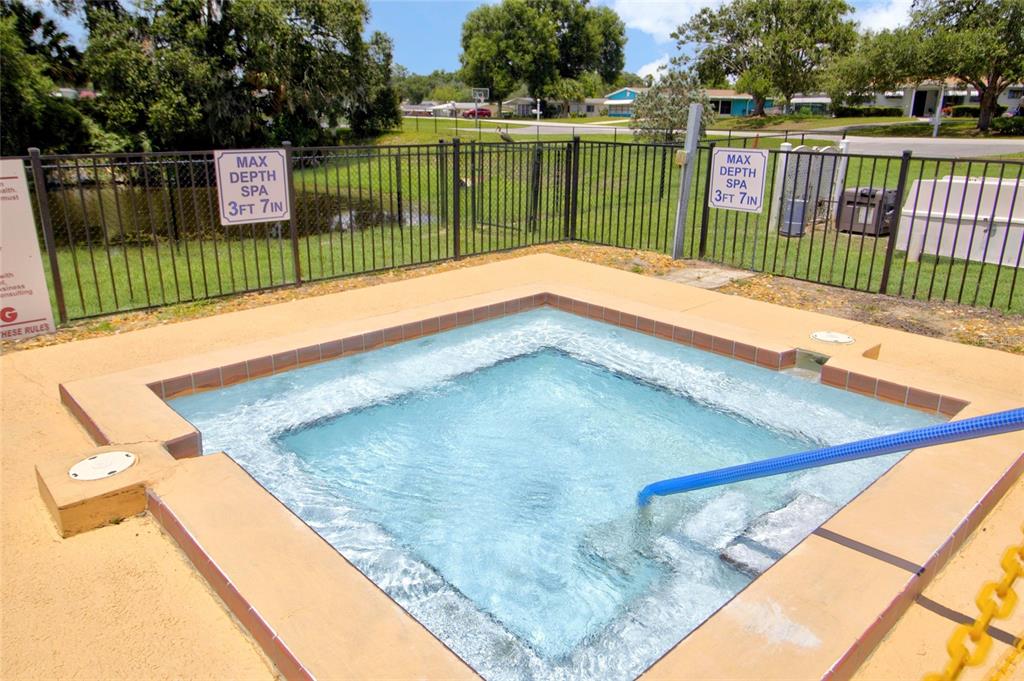 A square outdoor spa with a blue handrail is enclosed by a black metal fence — 10081 SW 95TH AVENUE, OCALA, FL