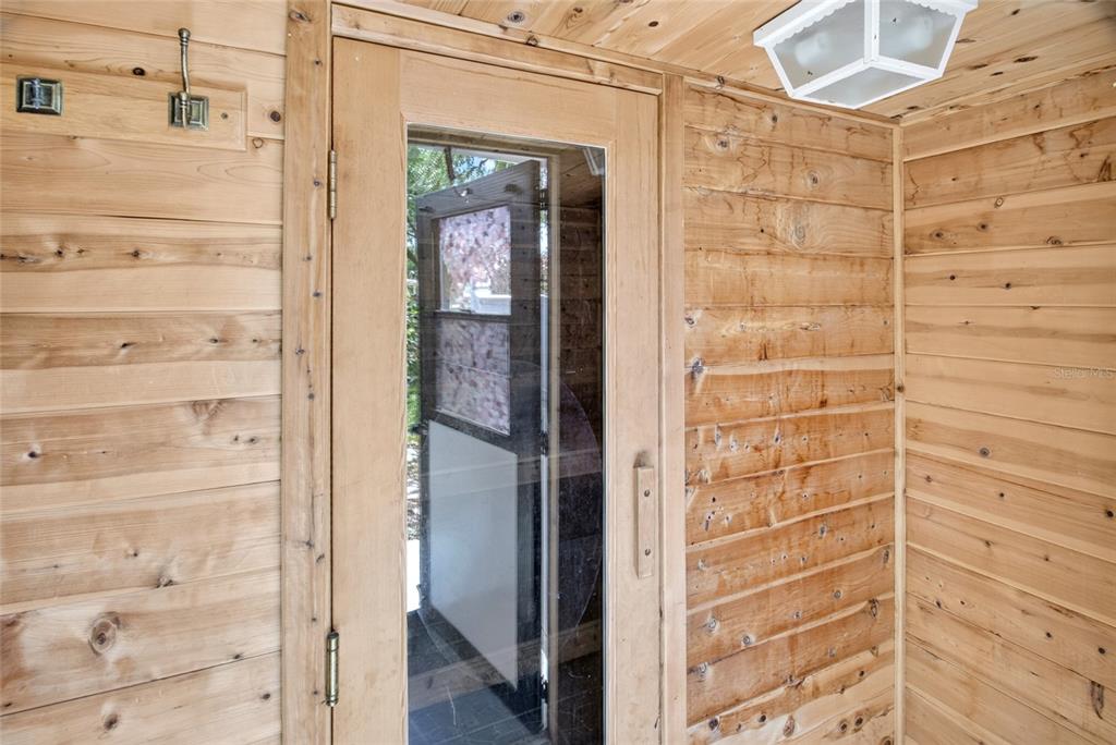 A sauna interior featuring light wood paneling, a glass door, and a ceiling light fixture — 10081 SW 95TH AVENUE, OCALA, FL