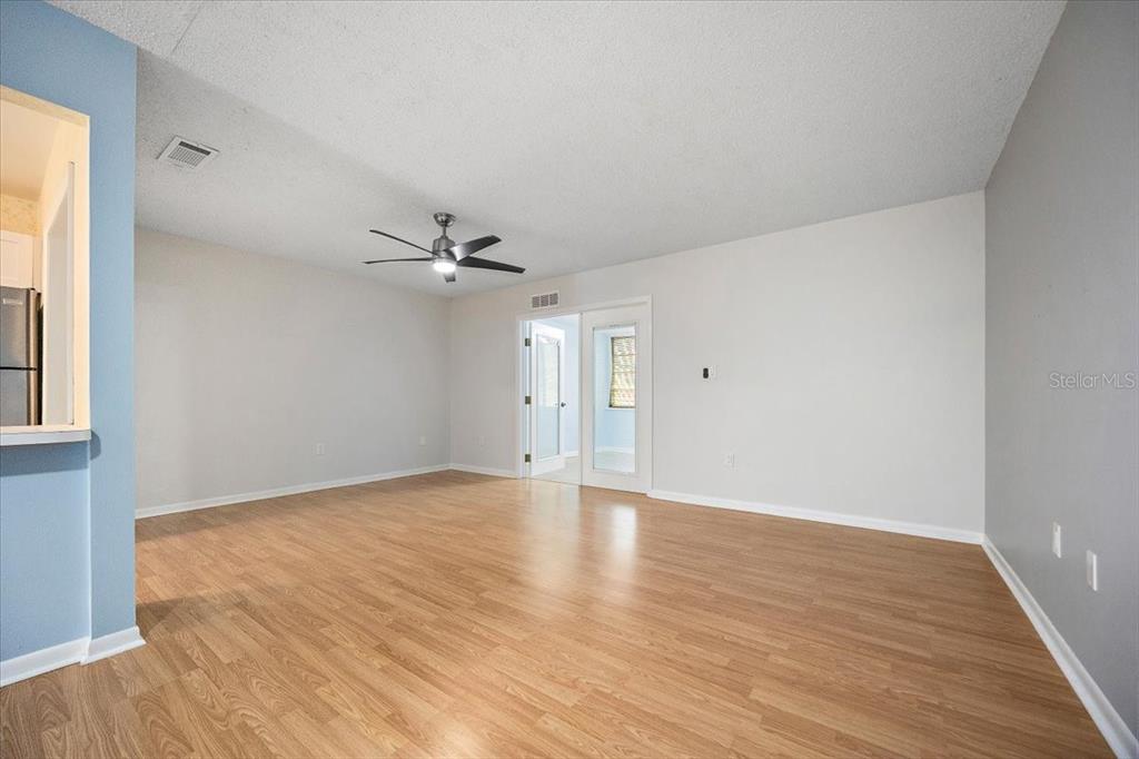 An empty living room features light wood-look flooring, gray walls, and a ceiling fan — 2628 SW 14TH DRIVE UNIT 326, GAINESVILLE, FL
