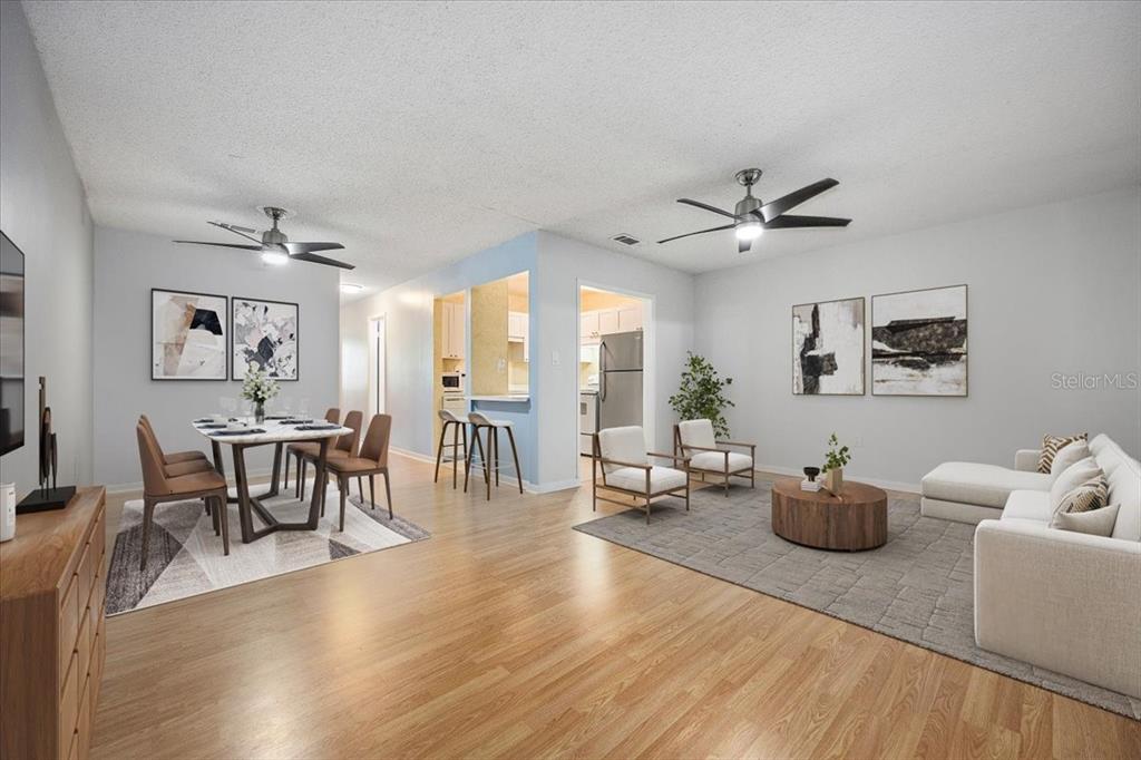 This open-concept living and dining area features light wood floors and two ceiling fans — 2628 SW 14TH DRIVE UNIT 326, GAINESVILLE, FL