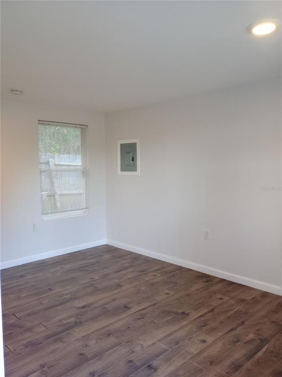 An empty room with light-colored walls, wood-look flooring, a window, and an electrical panel — 4748 US HIGHWAY 17 UNIT 14, DE LEON SPRINGS, FL