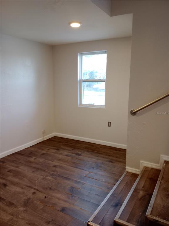 A room with wood-look flooring, a single window, and stairs with a metal handrail — 4748 US HIGHWAY 17 UNIT 14, DE LEON SPRINGS, FL