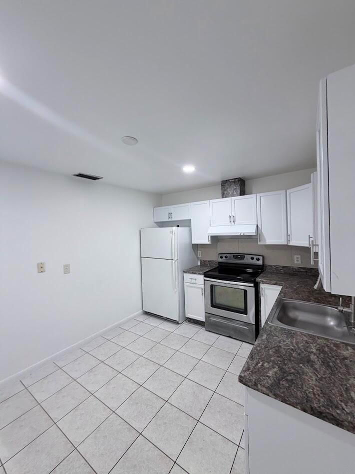 A kitchen features white cabinets, stainless steel appliances, dark countertops, and light-colored floor tiles — 5899 Mango Road, West Palm Beach FL 33413, WEST PALM BEACH, FL