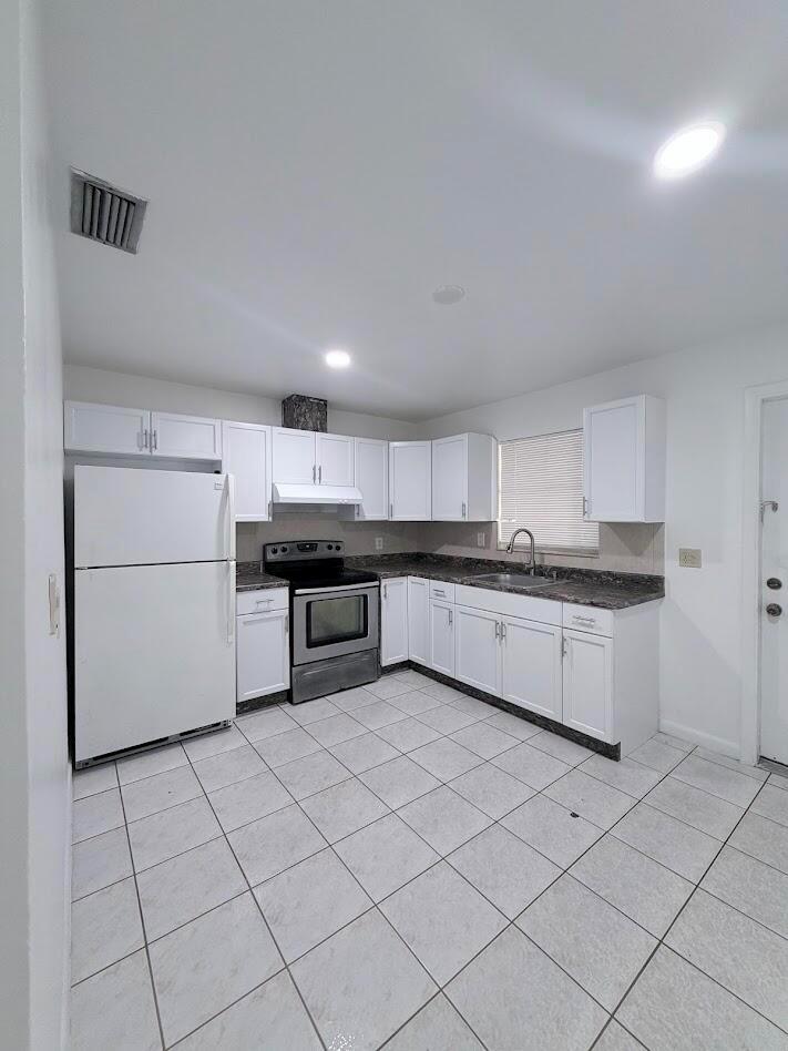 A kitchen features white cabinets, stainless steel appliances, dark countertops, and white tile flooring — 5899 Mango Road, West Palm Beach FL 33413, WEST PALM BEACH, FL