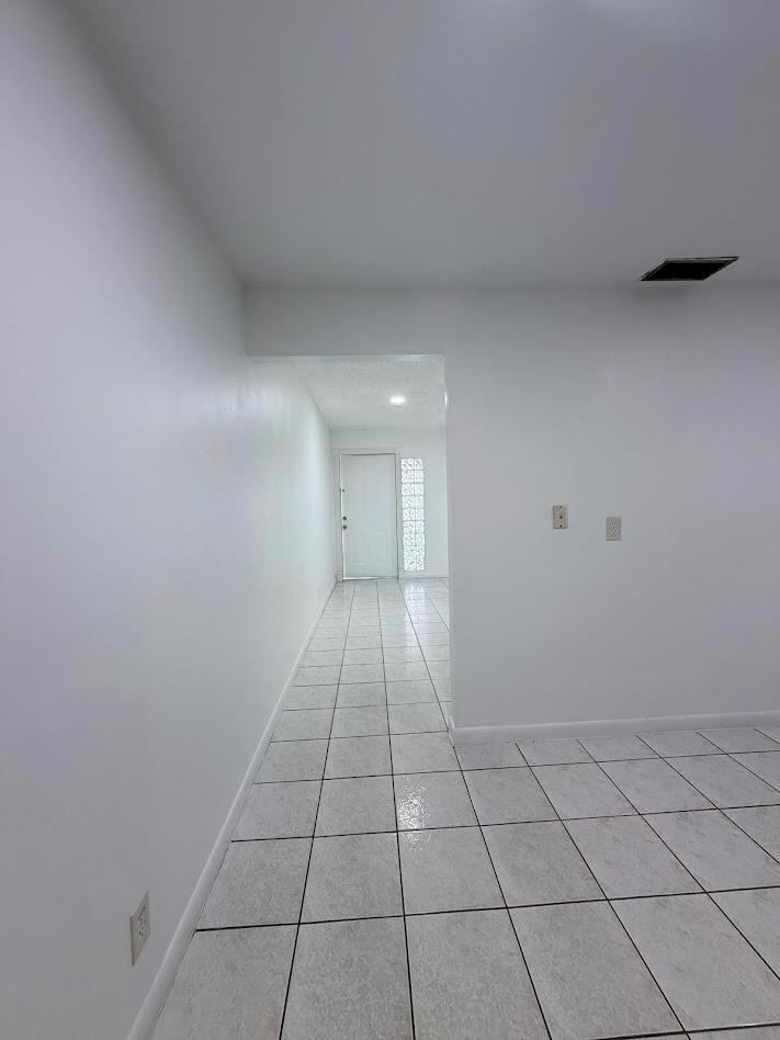A white-walled room with light-colored tiled floors leads to a doorway with glass blocks — 5899 Mango Road, West Palm Beach FL 33413, WEST PALM BEACH, FL
