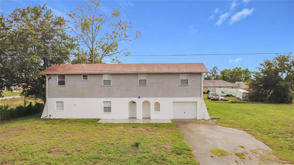 A two-story house with gray siding, a white stucco lower level, and an attached garage — 3303 6TH STREET SW, LEHIGH ACRES, FL