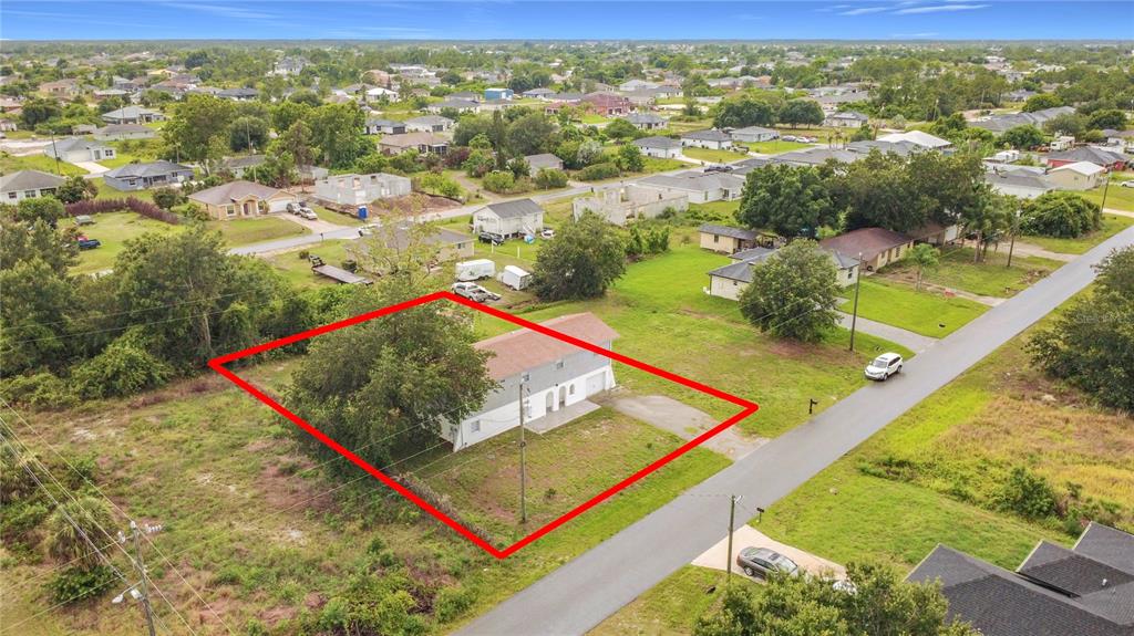 An aerial view shows a two-story house with a red roof on a grassy lot — 3303 6TH STREET SW, LEHIGH ACRES, FL