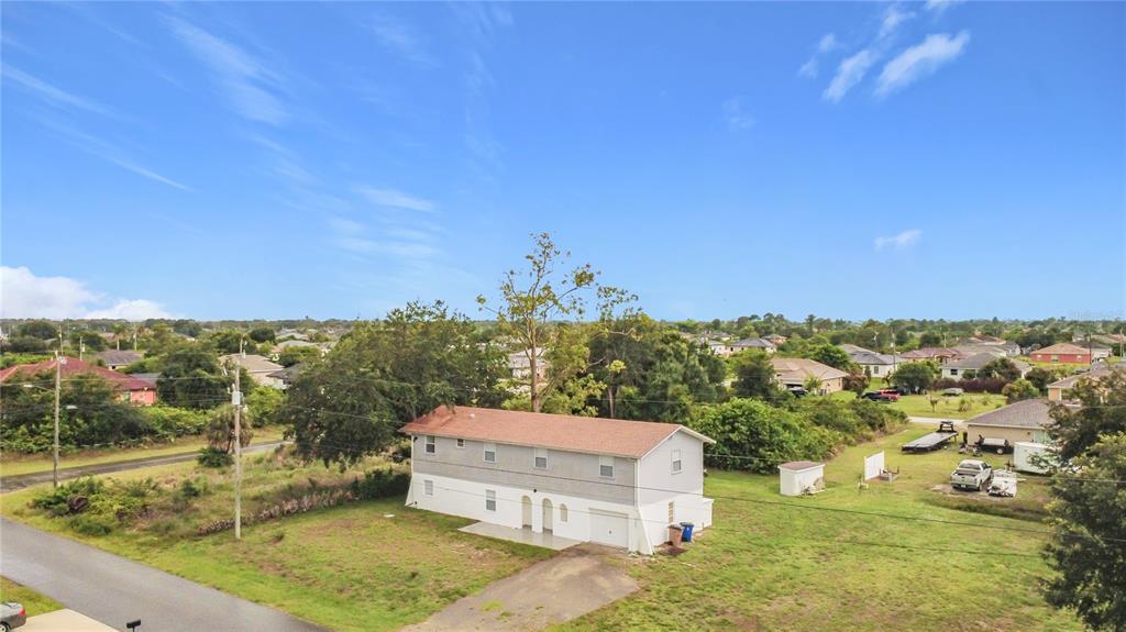 An aerial view shows a two-story house with a white lower level and gray siding — 3303 6TH STREET SW, LEHIGH ACRES, FL