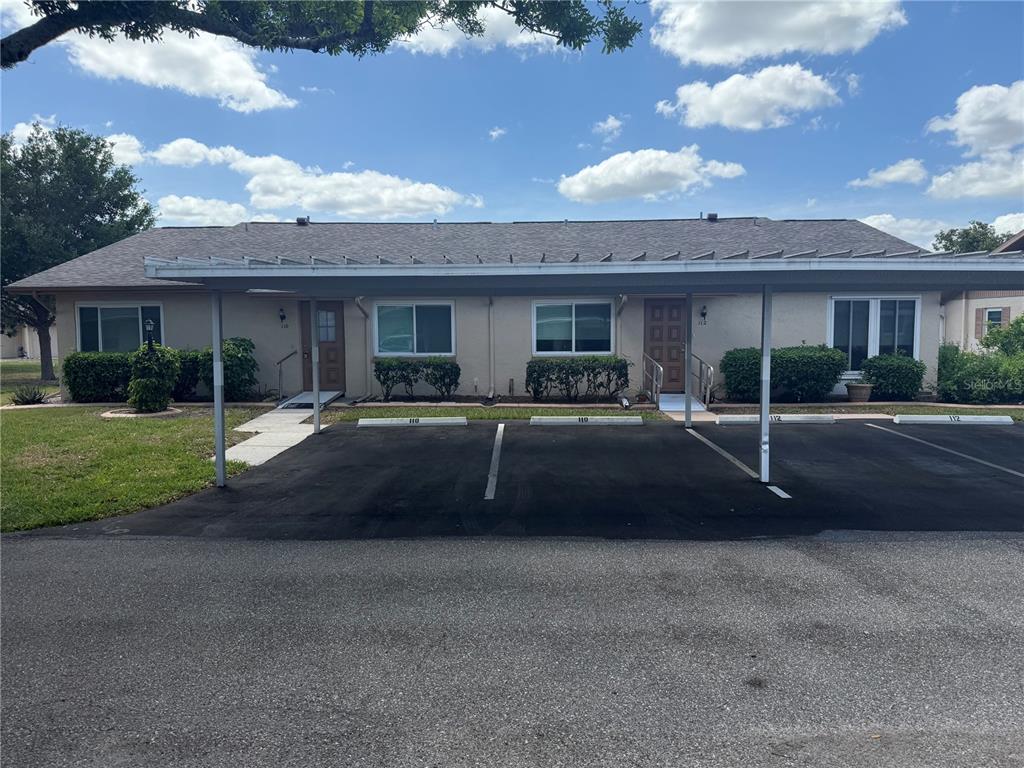 A single-story duplex building with a shared carport and parking spaces in front — 110-112 GLOUCESTER BOULEVARD, SUN CITY CENTER, FL